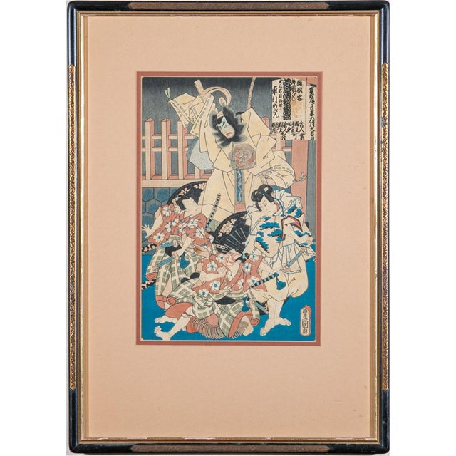 A pair of framed woodblock prints depicting dramatic scenes from kabuki theater. The left print shows a seated warrior...