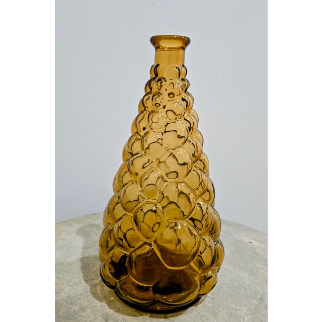 Warm and sculptural mid‑century Empoli glass genie bottle in rich amber, molded in a distinctive stacked bubble pattern...