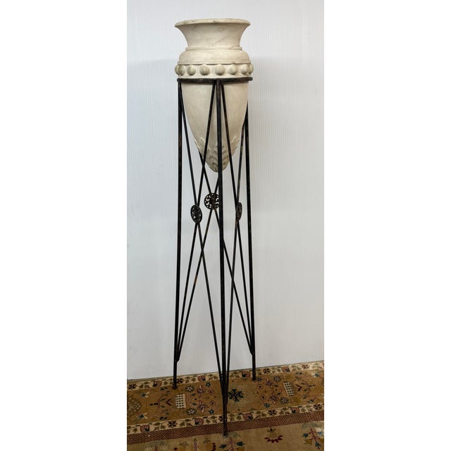 Design Plus Gallery presents an Iron Tripod Stand + Ceramic Urn. the tall, slender wrought iron frame has a triangular...