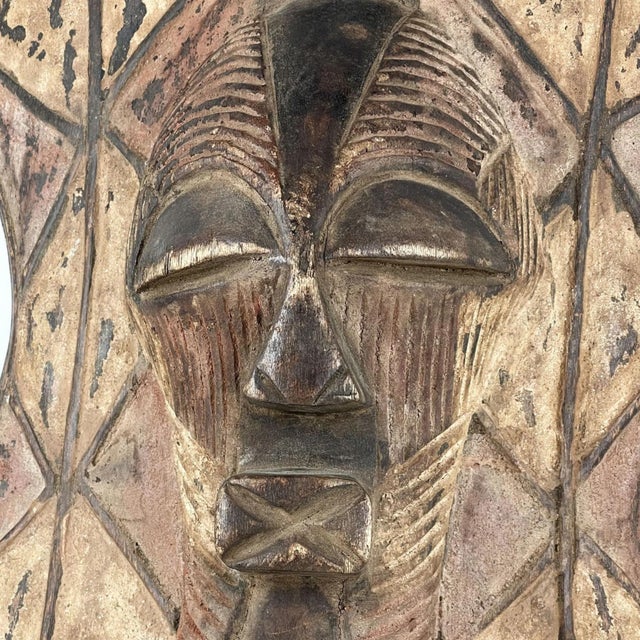 The wooden shield featuring a Kifwebe mask at its center was prevalent in the Songye region during colonial and pre-...
