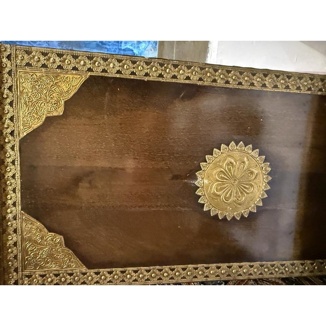 A beautifully crafted vintage wooden cabinet featuring intricate brass panel detailing and traditional hand-carved...