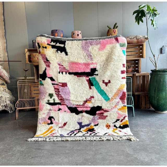 This Moroccan rug features a captivating color palette, showcasing a unique and intricate geometric pattern. The design...