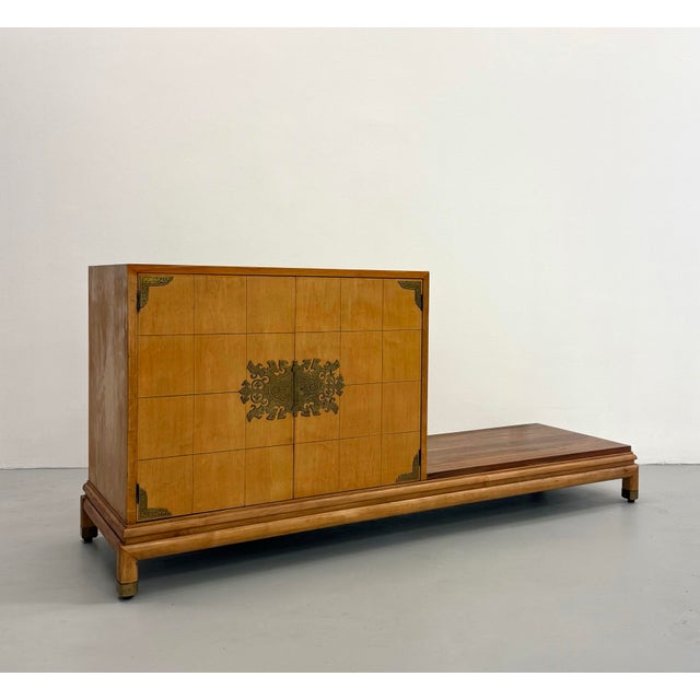 A gorgeous platform credenza featuring clean architectural lines and an asymmetrical integrated base. Crafted in a warm...