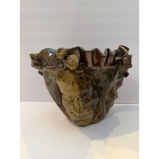 Striking vintage studio pottery vessel featuring sculptural human faces encircling the body with an expressive organic...