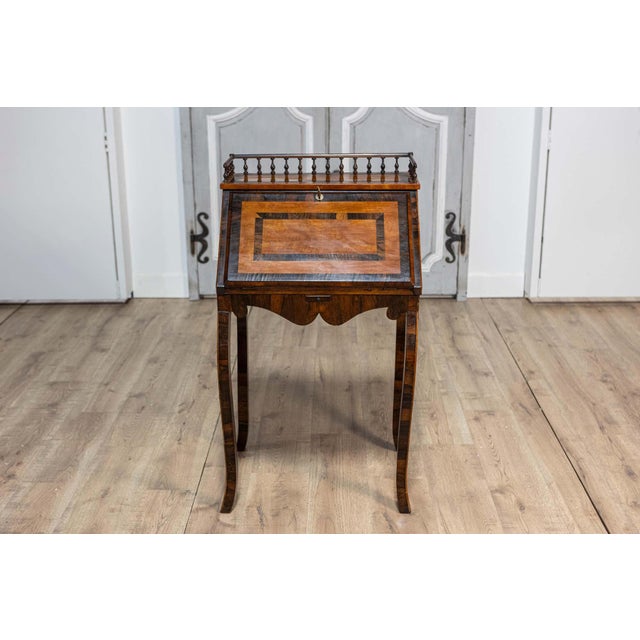 A petite Italian two-toned walnut and mahogany writing desk from the 19th century with slant front, turned three-quarter...