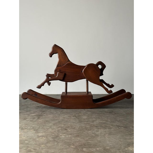 Carved from solid pine with a flowing, sculptural silhouette, this vintage rocking horse plants its front legs mid-stride...