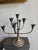 A sculptural vintage brass candle holder featuring six gracefully adjustable curved arms, each ending in a flared,...