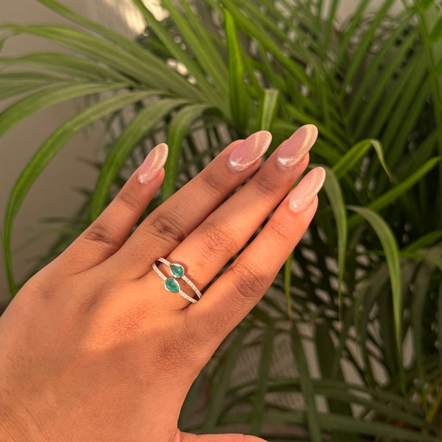 This open ring featuring a 0.67 carat pear cut natural emerald, set in 14K white gold. Each emerald measures approximately...
