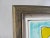 This wood framed tile was used as wall art, and still has the claw picture hanger with two felt pads on the back in the...