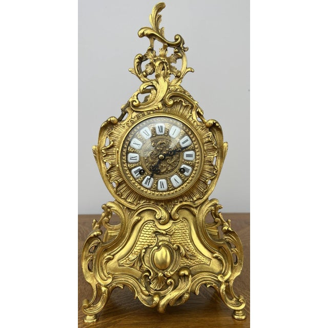 An elegant Vintage brass clock featuring a beautifully ornate Rococo-inspired design with flowing curves, pierced...