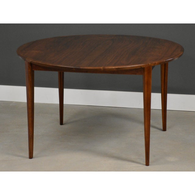 A mid century modern walnut round dining table with two 19.625” leaves that fully extend the table to 86.25” when...