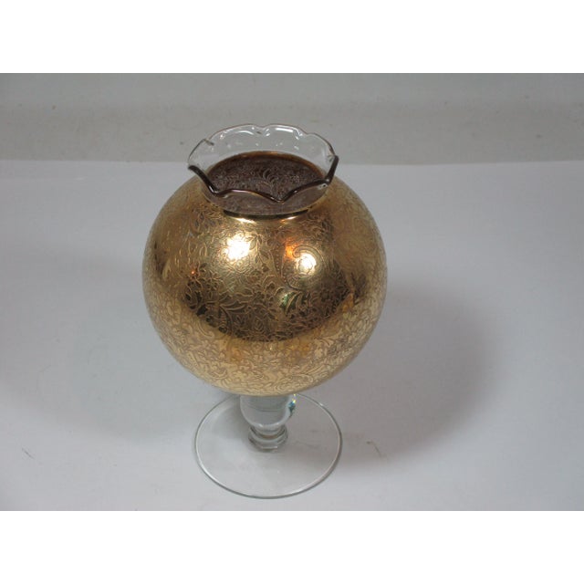 Hollywood Regency round glass vase with gold overlay, a clear stem and ruffled rim. The gold overlay has a allover...