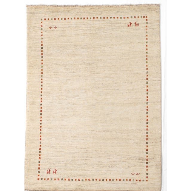 Vintage Hand-knotted Persian Lori Gabbeh rug featuring a soft ivory field enclosed by a delicate border of small...