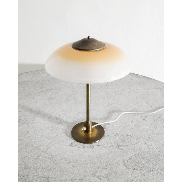 A rare and decorative Danish mid century desk table lamp in patinated brass with a beautiful frosted yellow white opaline...