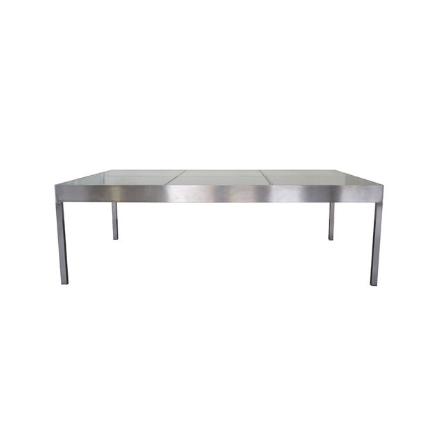 A sleek pair of modernist coffee tables featuring architectural brushed-steel frames inset with removable frosted-glass...
