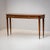 Walnut console table with two drawers and tall tapered legs. The handles are made of brass. The slightly bowed console has...