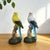 This charming pair of realistic parakeet figurines brings a touch of nature and color to any interior or garden space....