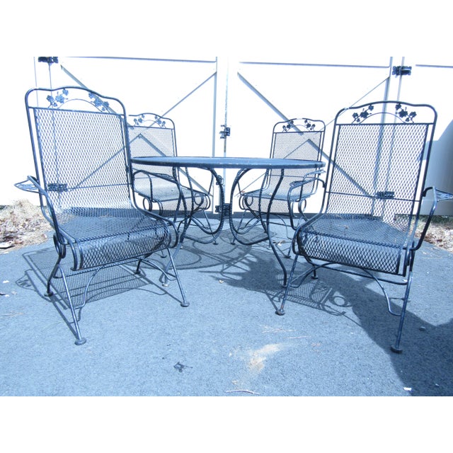 This vintage metal outdoor dining set combines four metal armchairs with a rounded table, all in a design that features...