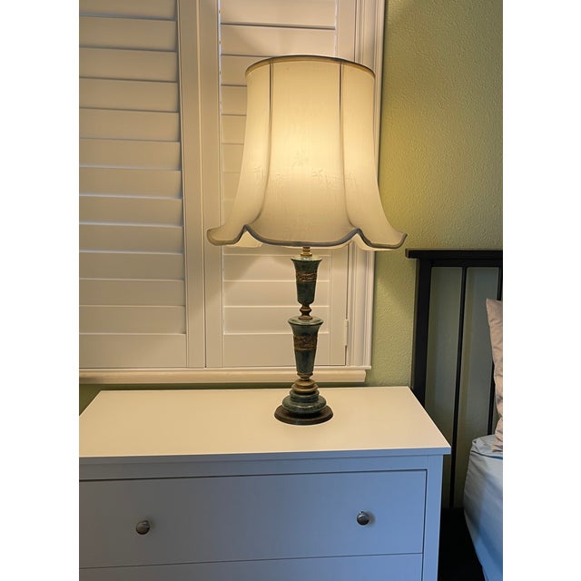 Elegant table lamps constructed with a green malachite and brass base. The lamp have tall, cream-colored fabric shades...