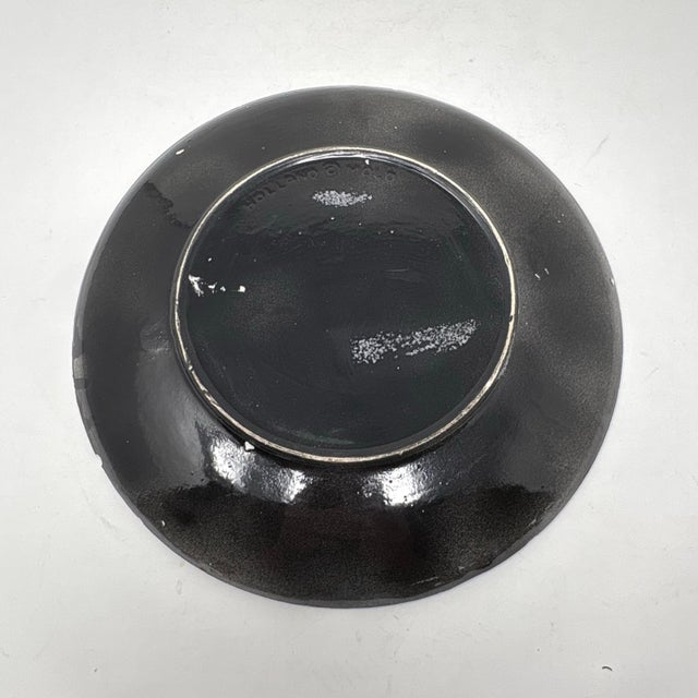 A vintage ceramic decorative dinner plates, with a black glossy glaze and pink and yellow splatter accents.