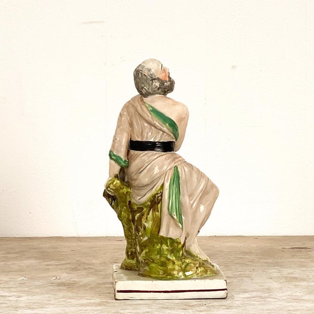 An early 19th-century English Staffordshire of Elijah and the Raven, circa 1800. The figure of Elijah is dressed in a...