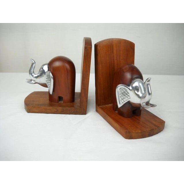 Stylized elephant bookends crafted of brushed aluminum and carved wood . No maker's mark.