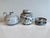 This handcrafted ceramic set, consisting of a lidded box, a handled vase, and two candlesticks, showcases the...
