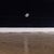 This artwork presents a minimalist composition featuring a stark contrast between a deep black surface and a muted,...