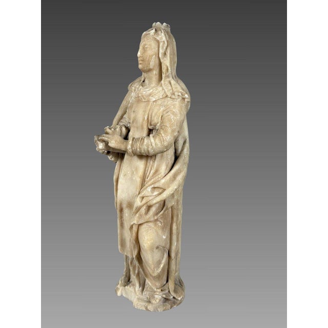 Alabaster sculpture of Saint Anne, 16th century. Depicts Saint Anne crowned, holding a book upon which rests a crown...