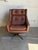 This swivel lounge chair features a curved shell upholstered in rich brown leather with tufted cushions. Its expressive...