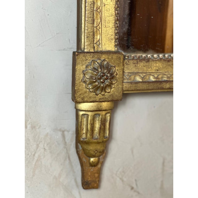 An elegant Louis XVI period mirror in carved and gilded wood, surmounted by an openwork pediment depicting a bird...