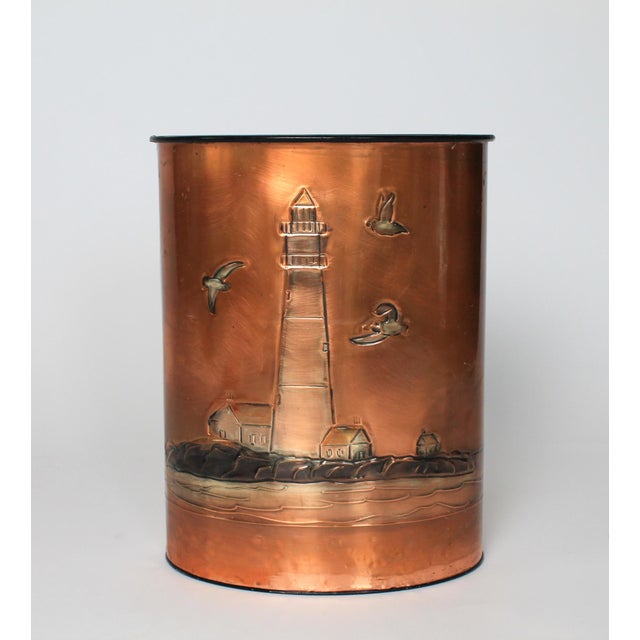 Vintage oval metal waste basket wrapped in an embossed copper sheet featuring a nautical lighthouse and seabirds scene....