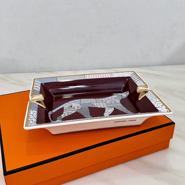 This is a classic Hermès bone china storage tray that functions as both an ashtray and a jewelry tray. It comes with a...