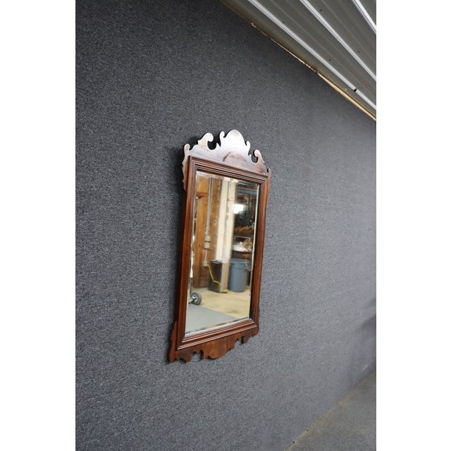 Mahogany wall mirror by Councill Craftsmen featuring a carved scroll crest and molded frame. Classic traditional design...