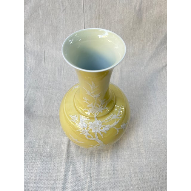 Vintage porcelain bottle flower vase featuring raised white slip design depicting branches and birds.