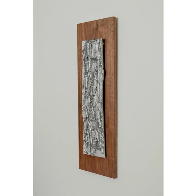 Dimensions: Dimensions: 10" x 31.5" Brutalist cast aluminum relief mounted on teak board, U.S., circa 1970's.