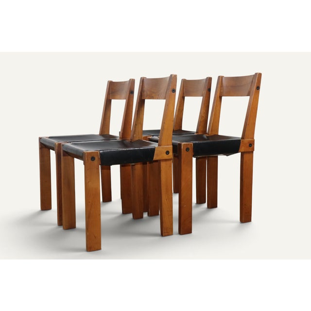 Set of four S24 model chairs, designed by Pierre Chapo in 1967, combining a solid elm frame with a black leather seat....