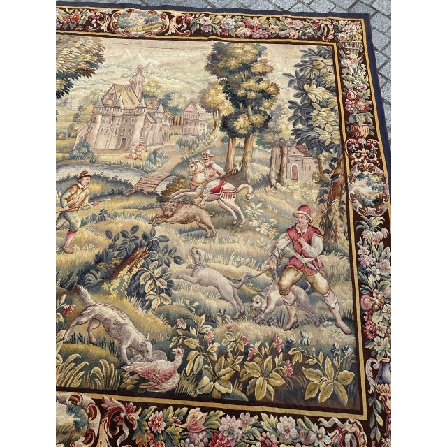 Impressive early 20th-century Aubusson tapestry depicting a lively pastoral hunting scene, rich in detail and color. At...