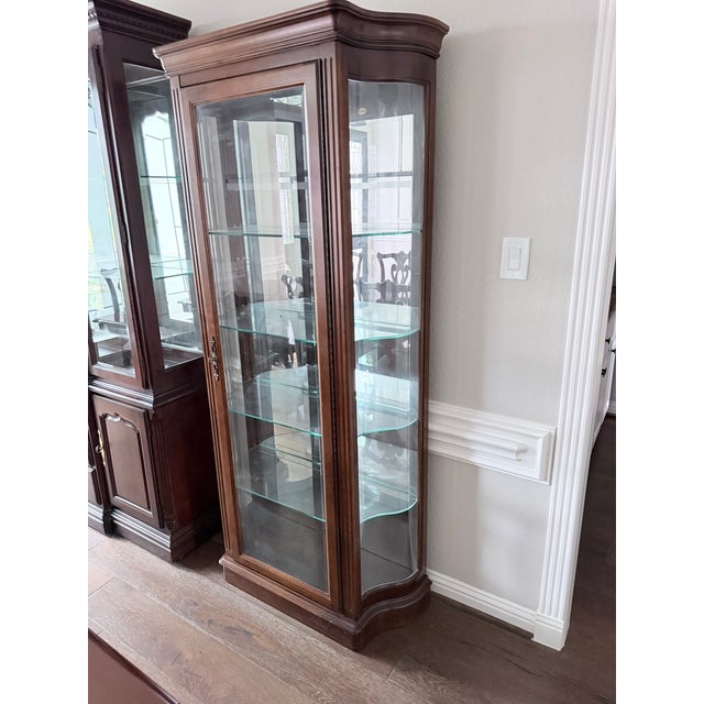 Item is marked as Thomasville (shown in 3rd photo). An elegant standalone curio cabinet with a distinctive curved glass...