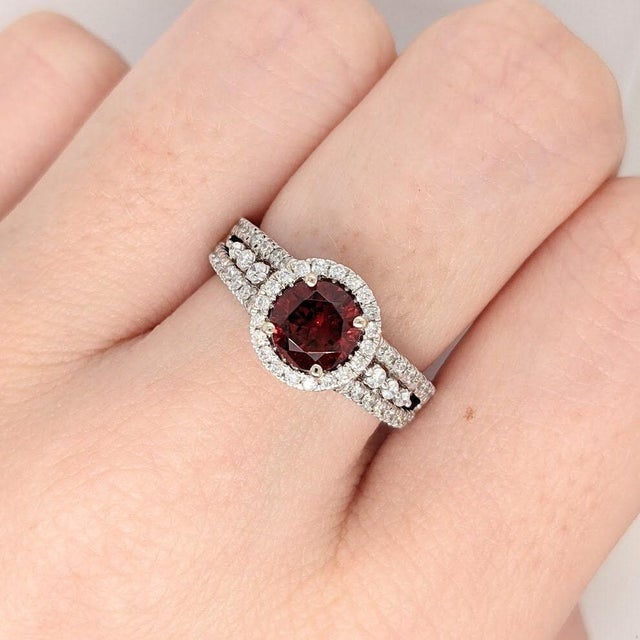 A spessartine garnet rests in a deep red at the heart of this solid 14K white gold ring, accented with earth-mined...
