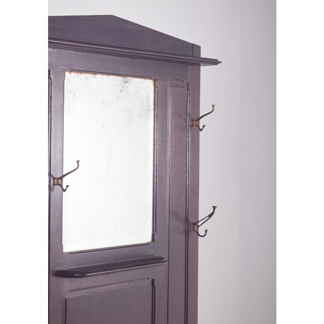 Coat rack with mirror. A functional and robust piece, ideal for entrances or corridors. In dark wood, its design is sober...