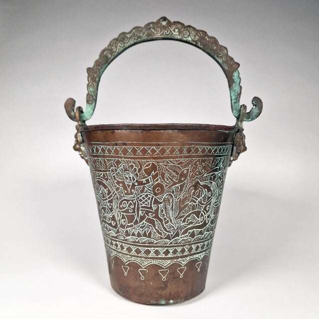 On offer is this ornately decorated Indian copper bucket. It features cast brass lion head mounts and an incised...