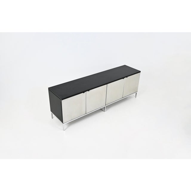 Black wood sideboard with metal legs and four brushed steel doors, containing two height-adjustable shelves. Stamped...