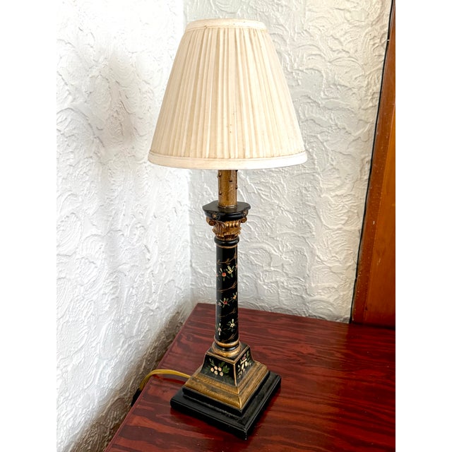 Mid 20th century black and gold Corinthian column table lamp with hand painted florals and a gold drip candle sleeve. A...