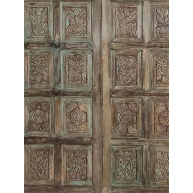 Crafted from reclaimed wood and finished in a timeworn green patina, this artisan-carved vintage door panel exudes rustic...