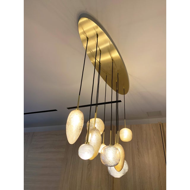 Mouth-blown glass pendants with 10 lights on a brass finish oval canopy. Inspired by the "Vallons Obscurs" of the Var...