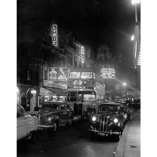 Street Night 29th September 1954: A bus and cars travelling down Shaftesbury Avenue, London, in front of an illuminated...