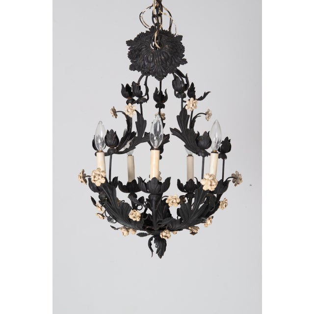 A metal floral Italian chandelier painted black with white painted metal flowers. It has five chandelier size sockets and...