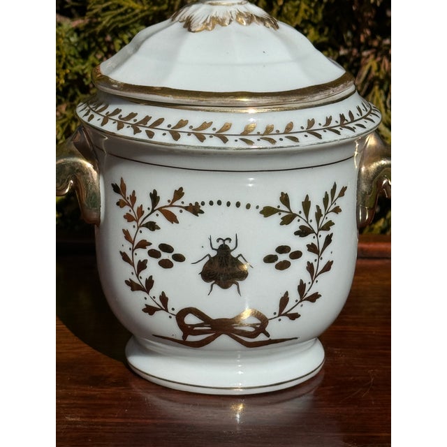 Vintage porcelain cachepot with lid, featuring gold leaves and bee with a bow designs. Historically, bees are symbolic of...
