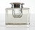 A heavy, square block-form glass inkwell with thick, clear walls and beveled edges. It has a round, domed silver or...